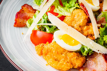 salad with fried chicken and bacon on a black background