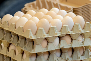 Stacked in layers of fresh white duck eggs in the tray for sale in the market stall, A pile of eggs in brown paper panels in the kitchen for cooking.