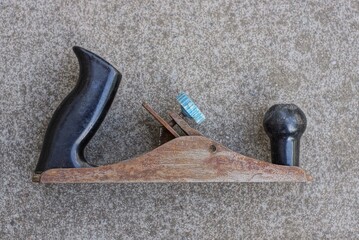 one old metal jointer in brown rust with black handles lies on a gray table