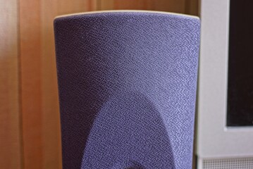 part of one audio speaker in purple fabric on a brown background in the room