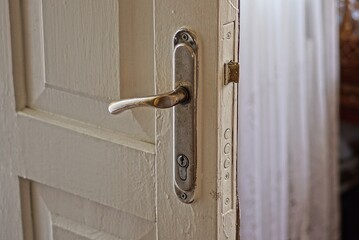 white wooden open door with gray metal door lock and door handle in the room