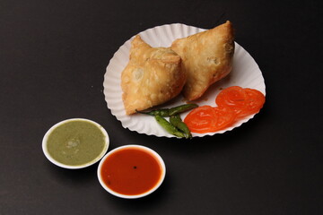 India's favourite snack item samosa served with jalebi on paper plate 