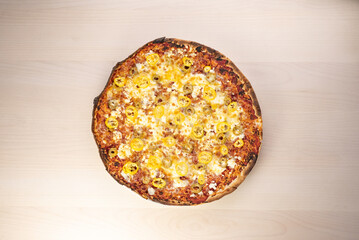 Delicious three cheese pizza with olives and yellow pepper on a table close-up shot 