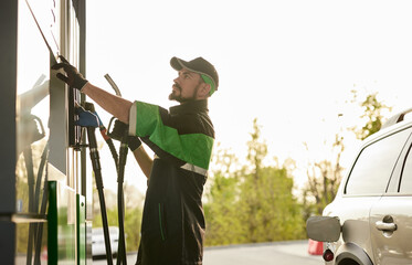 Serious male worker choosing fuel at gas station