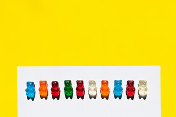 Top view of row from gummy bears on white and yellow.