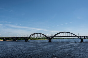 Fototapeta na wymiar large metal railway bridge across the river against the blue sky