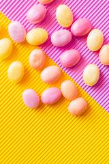 Top view of colorful sweets on textured pink and yellow background.