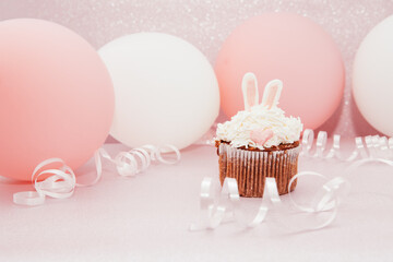 Cupcake in bunny form on glitter pink background with air balloons, beautiful celebration card