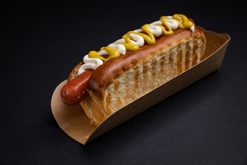 Hot dogs in paper plates with sausages and sauce 
