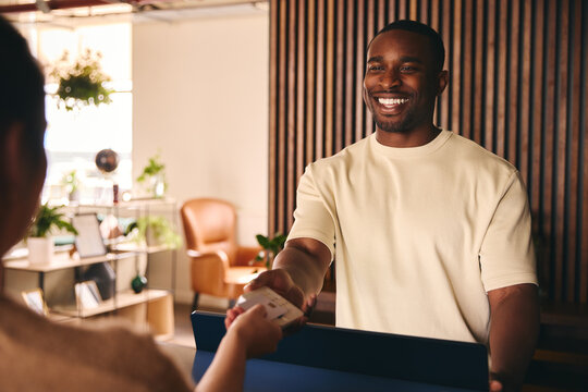 Happy Sales Assistant In Retail Shop With Customer Paying Using Contactless Payment Credit Card NFC