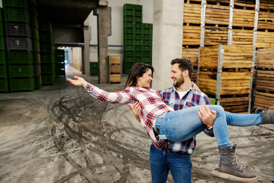 A couple who works together having fun at work in storage.