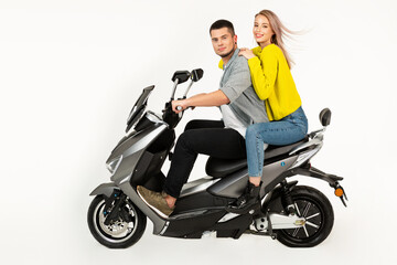 Obraz na płótnie Canvas young attractive couple riding an electric motorbike scooter happy having fun together