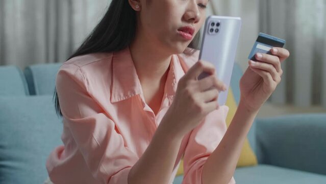 Close Up Of Asian Woman Holding Credit Card And Smartphone Shaking His Head Due To Unable Pay Money
