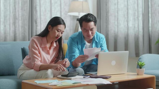 Asian Couple With A Laptop Helping Each Other Calculating Money By Calculator 
