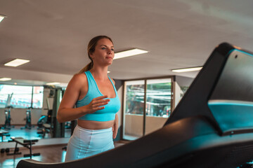 Fototapeta na wymiar blonde girl using a treadmill in the gym