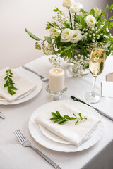 Wedding teble decoration with white flowers, glasses and white napkins. Elegantly decorated table at a wedding reception. Festive table setting. The wedding decor.