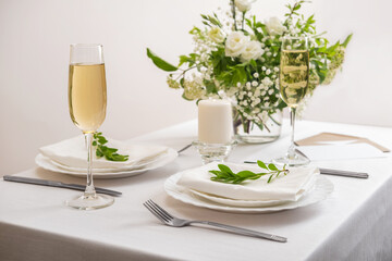 Wedding teble decoration with white flowers, glasses and white napkins. Elegantly decorated table at a wedding reception. Festive table setting. The wedding decor.