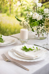 Wedding teble decoration with white flowers, glasses and white napkins. Elegantly decorated table at a wedding reception. Festive table setting. The wedding decor.