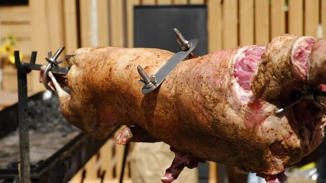 Roast Lamb on Spit. Crispy fat Lamb on skewer grilled using hot charcoal. Whole lamb barbecue spitfire roasted. Appetizing grilled carcass of lamb close up. Cooking meat. Catering. Picnic or banquet.