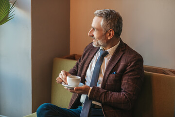 Meditating man with coffee sitting sideways to camera