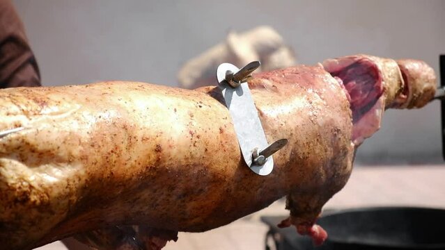 Roast Lamb on Spit. Crispy fat Lamb on skewer grilled using hot charcoal. Whole lamb barbecue spitfire roasted. Appetizing grilled carcass of lamb close up. Cooking meat. Catering. Picnic or banquet.