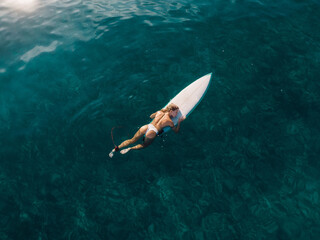 Aerial view of sexy surfer woman with surfboard in ocean.