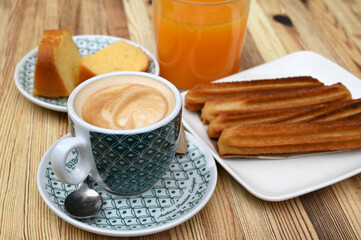 Tasse de café avec une assiette de churros et un verre de jus d'orange