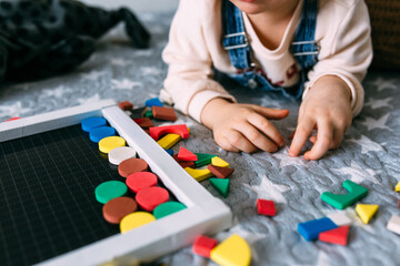 Child plays at home an educational game with a multi-colored magnetic puzzle