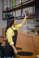 Woman sideways to camera placing glass on top shelf