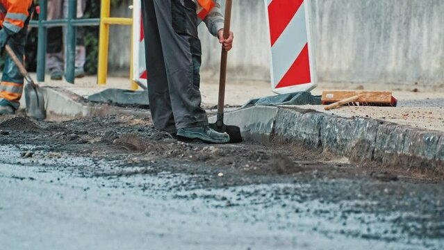 Roadworks Construction Worker Using Shovel Preparing Road For Laying New Asphalt Concrete Paving