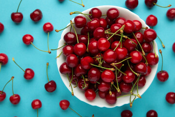 Fototapeta na wymiar Fresh sweet cherries in bowl on blue background