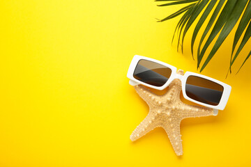 Starfish in sunglasses on a yellow background. Minimalistic humorous summer concept with copy space