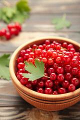 Bowl with ripe red currant on brown wooden background. Top view.