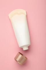 Top view blank label facial skincare tube bottle with lid open on pink background