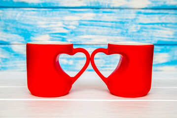 two heart shaped mugs with tea on Blue background
