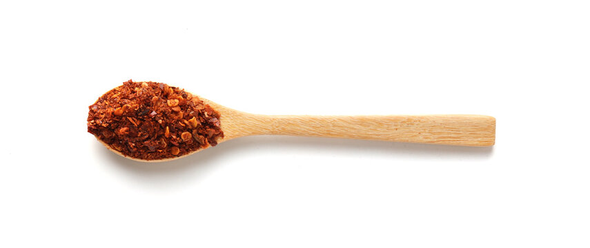 Cayenne pepper on a wooden spoon isolated on white background. Top view