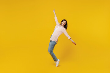 Full body young happy cool woman she 30s wear striped shirt white t-shirt stand on toes leaning back dance have fun fooling around isolated on plain yellow background studio. People lifestyle concept