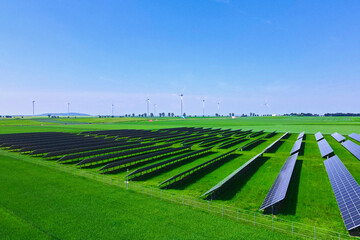 Solar panels battery in green field against blue sky, aerial view. Photovoltaic modules for...