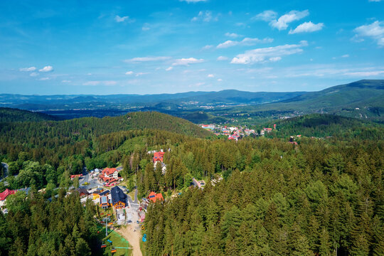 Aerial view of beautiful mountains, covered with forest and village. Karpacz resort in Poland with hotels. Family outdoor recreation in mountain