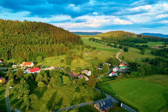 Overhead view of beautiful landscape at sunset, Aerial view of countryside area with village and green fields near mountains