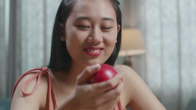Close Up Of Happy Asian Woman Biting An Apple While Having Healthy Food At Home
