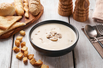 Fresh mushroom cream soup with croutons in a ceramic bowl on wooden table. Traditional soup puree served for lunch.   