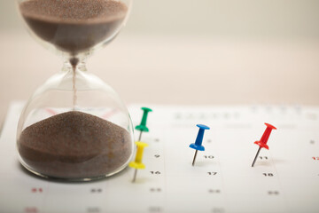 Pin and hourglass (sand clock) on the calendar, planning for a business meeting or travel planning concept, vacation, copy space