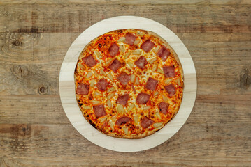 Iberian pizza with serrano ham, cherry tomatoes with black olives and mozzarella cheese on wooden table