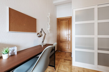 Room with industrial style wooden study table with gray resin chair and wood and glass sliding door wardrobe