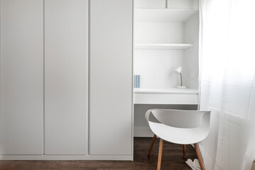 Small white wooden study table with resin and wood shelves and a chair next to a matching three-section cabinet