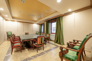 Boardroom with long green marble and wood table and many matching upholstered chairs