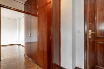 Hallway of a house with dark wooden doors, fitted wardrobes and herringbone oak parquet flooring