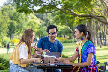 Group of college student is meeting and working on thesis and project outside in the university campus garden during summer