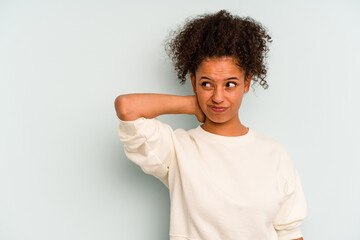 Young Brazilian woman isolated on blue background touching back of head, thinking and making a choice.